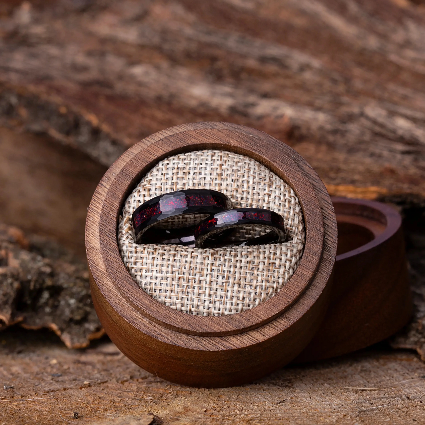 Two purple gemstone rings in a wooden box on a rustic wooden surface