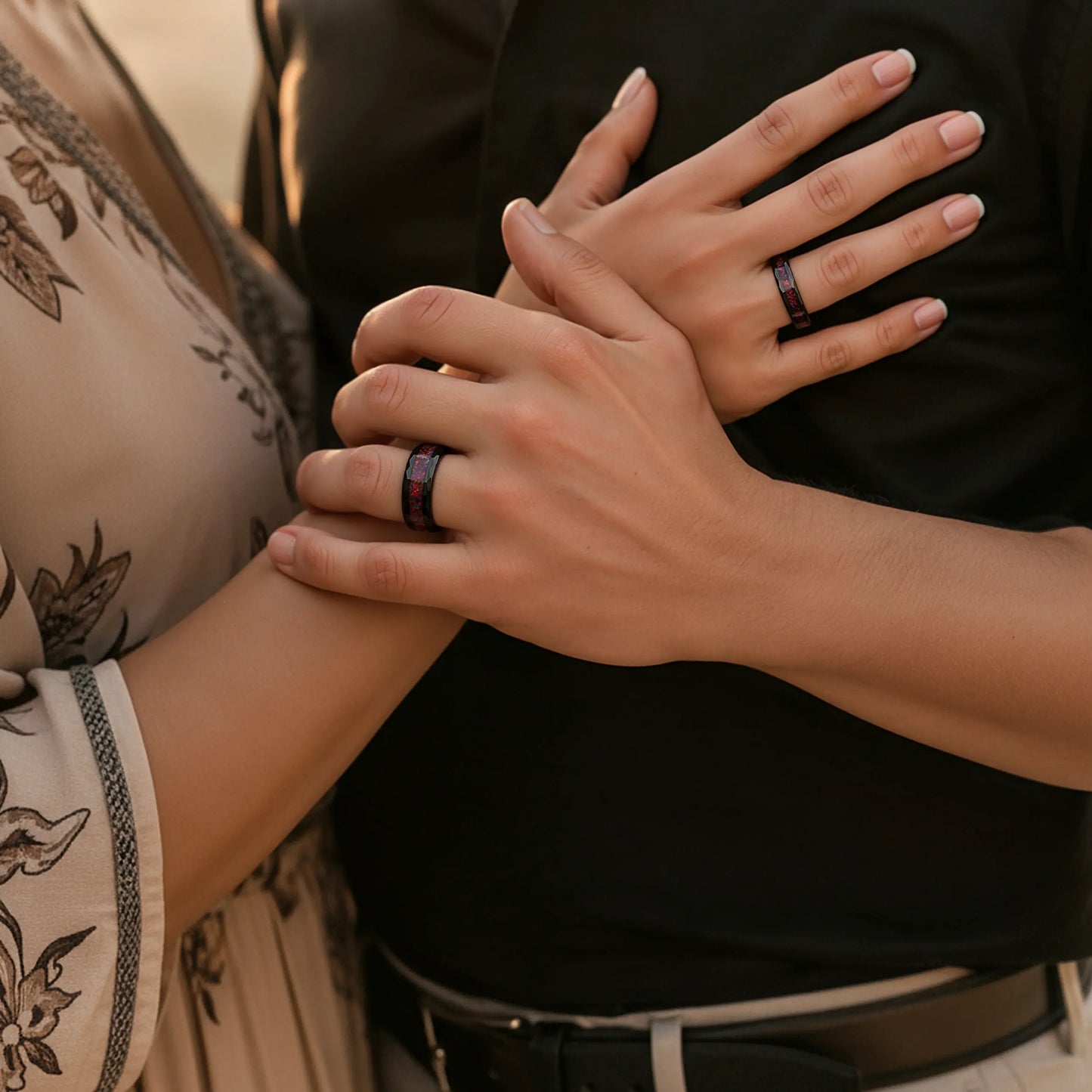 Close-up of two hands with a ring, one wearing a black shirt.