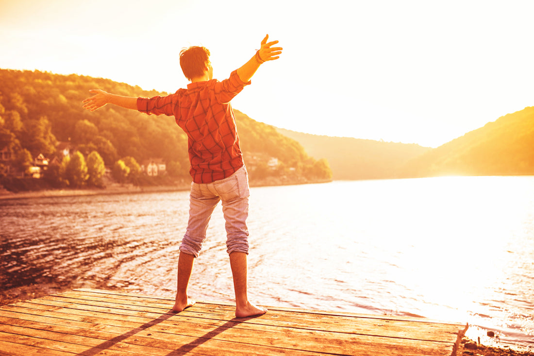 Man is staying on a bank of a lake on a sunset