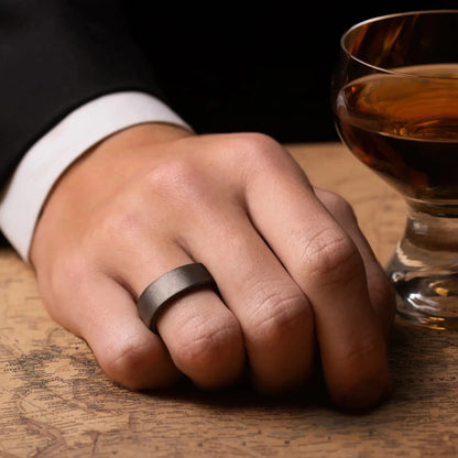 Grey tungsten ring with rosewood inlay. The ring is on a man's hand