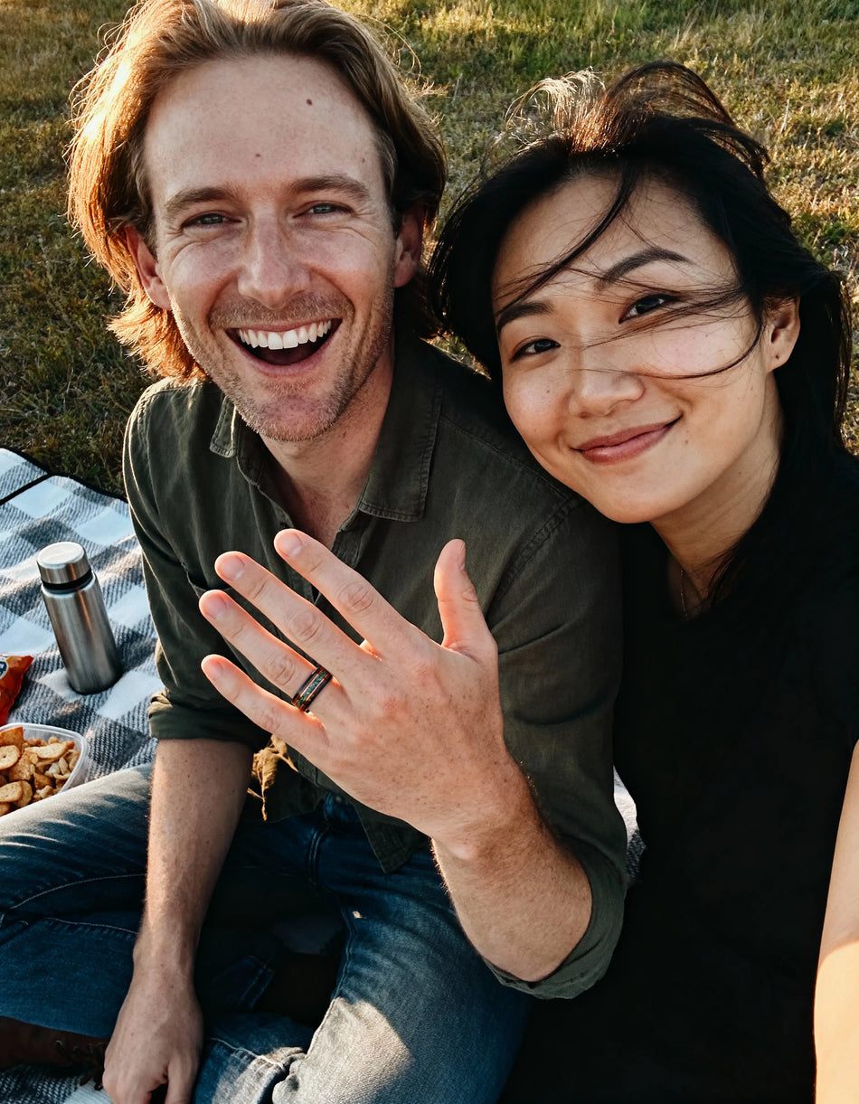 Man and woman sitting outdoors, smiling and posing for a photo.