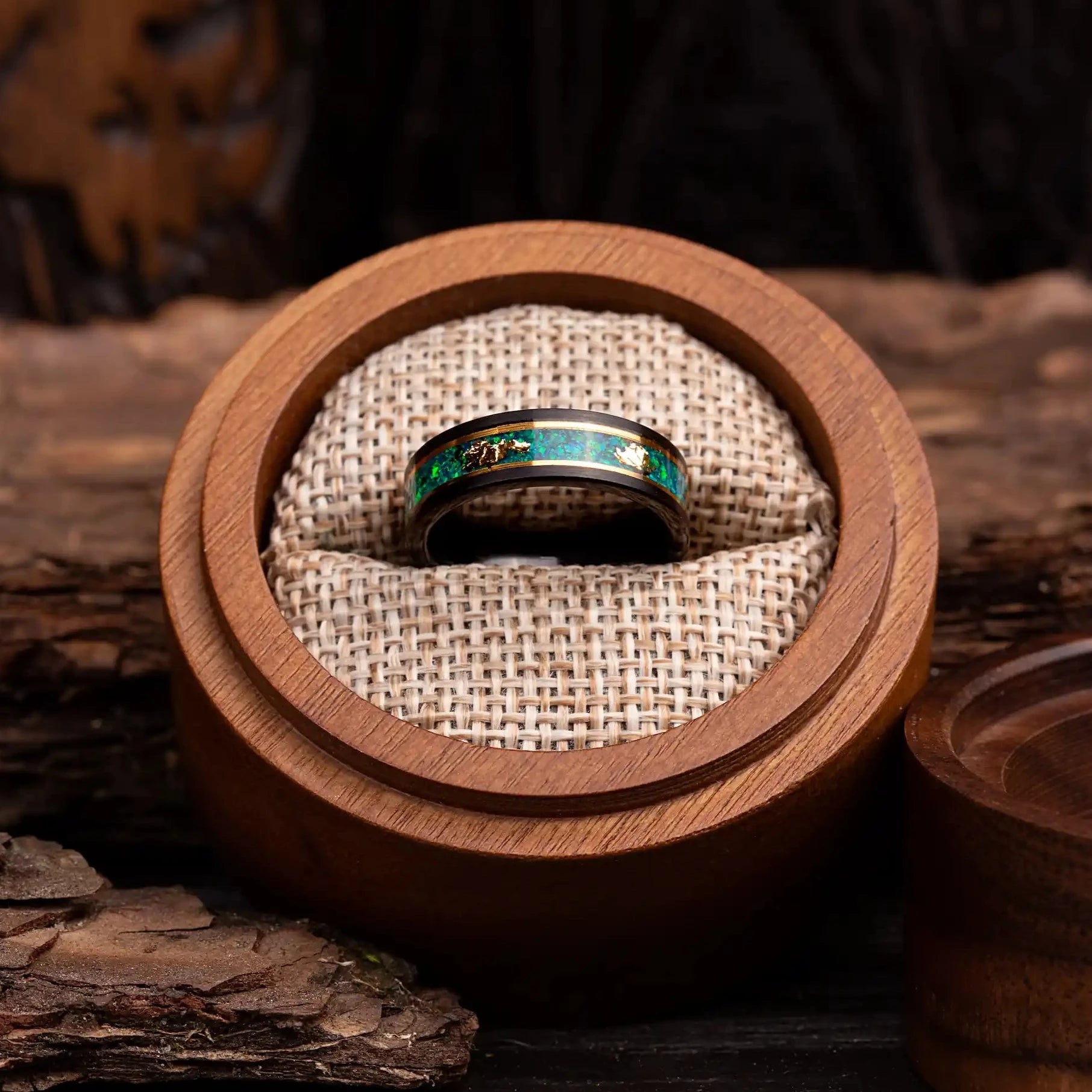 4mm Black polished tungsten ring with malachite and gold. The ring is placed inside a round wooden box