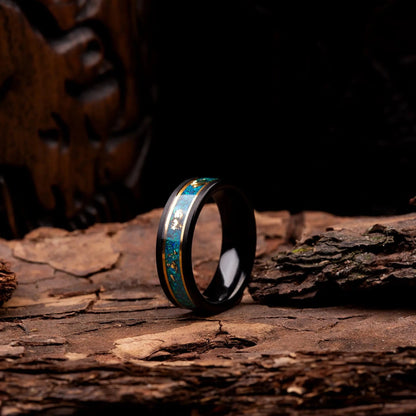 4mm Black polished tungsten ring with malachite and gold. The ring is placed on a wood