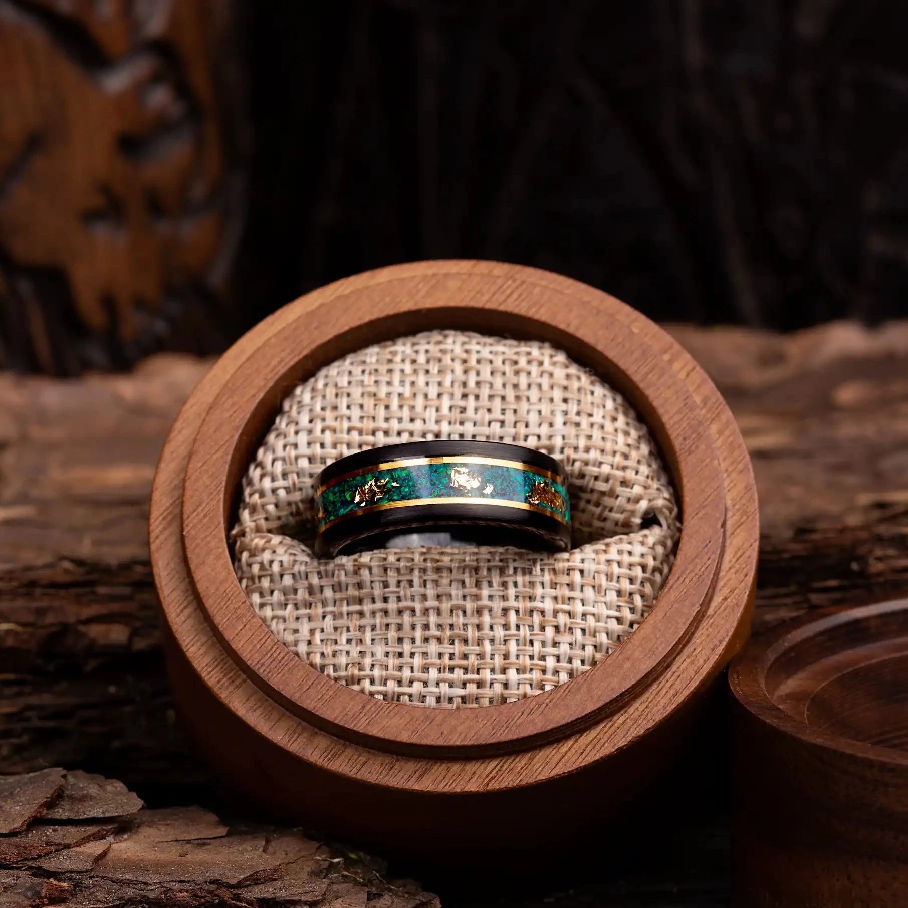 Black polished tungsten ring with malachite and gold. The ring is placed inside a round wooden box