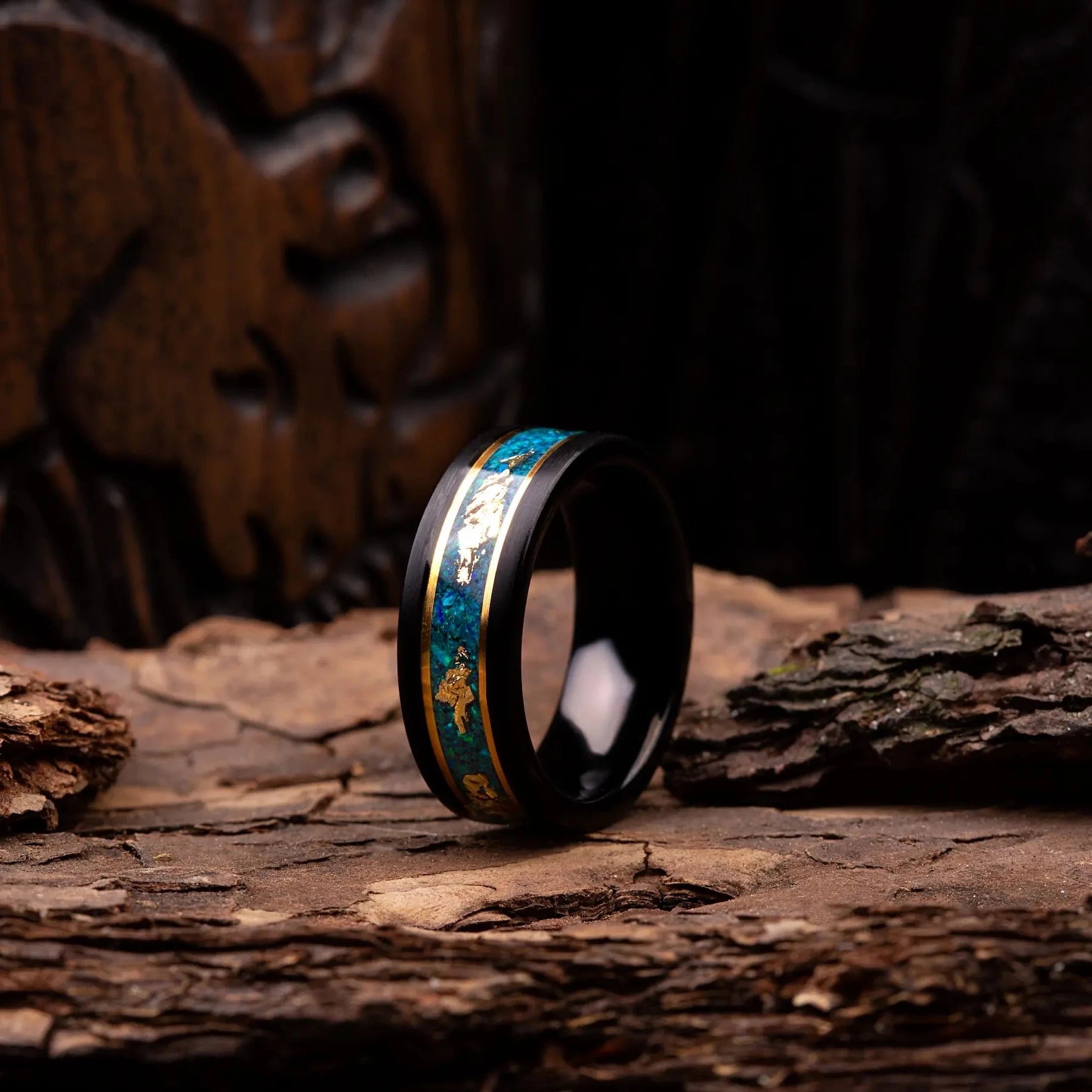 Black polished tungsten ring with malachite and gold. The ring is placed on a wood