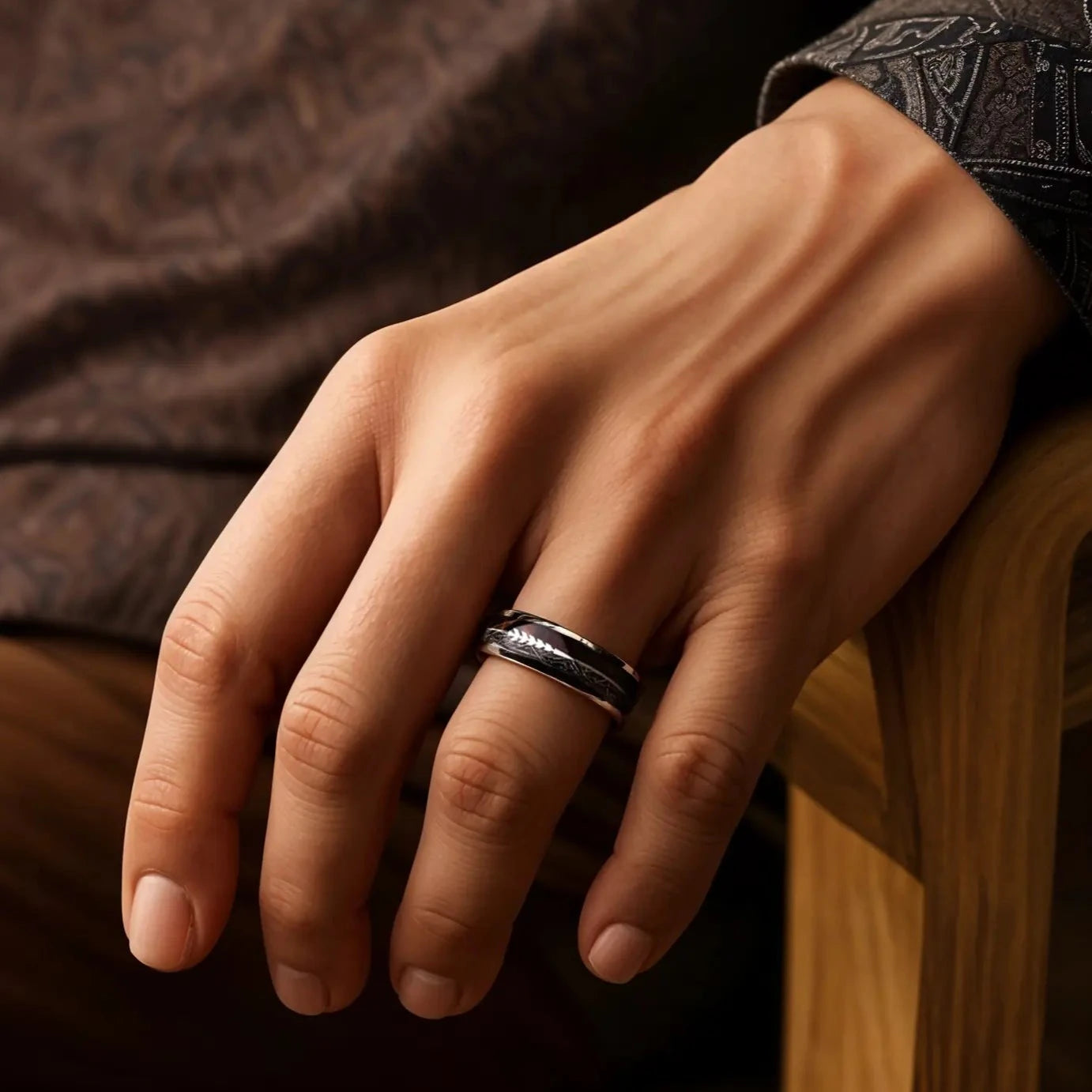 Silver tungsten ring with meteorite, rosewood and arrow sign. The ring is placed on a man's hand