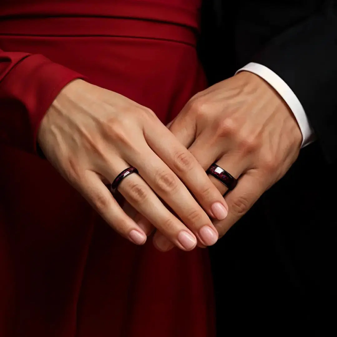 Close-up of hands holding each other with rings on a dark background