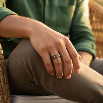 Close-up of a hand wearing a ring with a green shirt and brown pants.