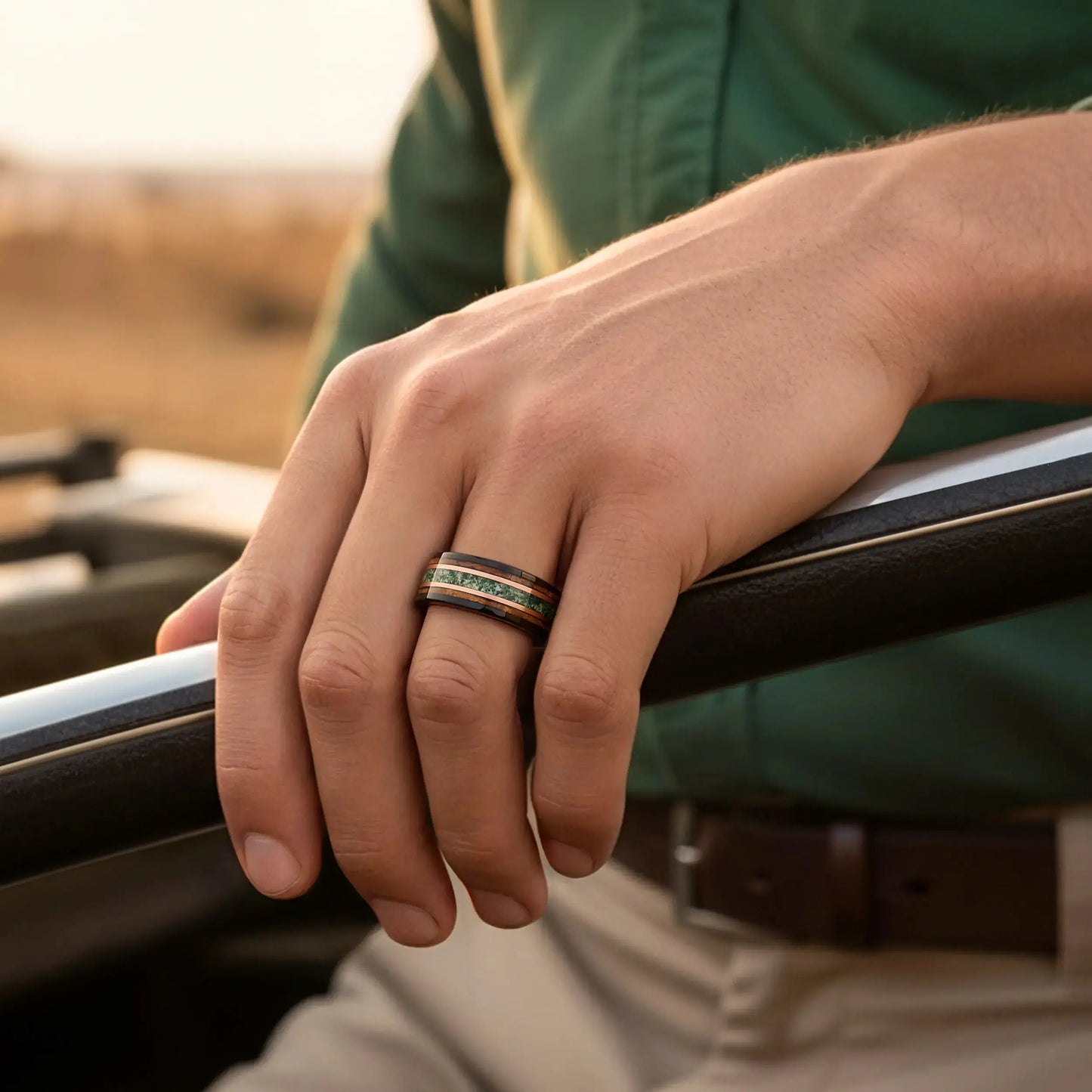 Hand holding a steering wheel with a ring on a blurred outdoor background