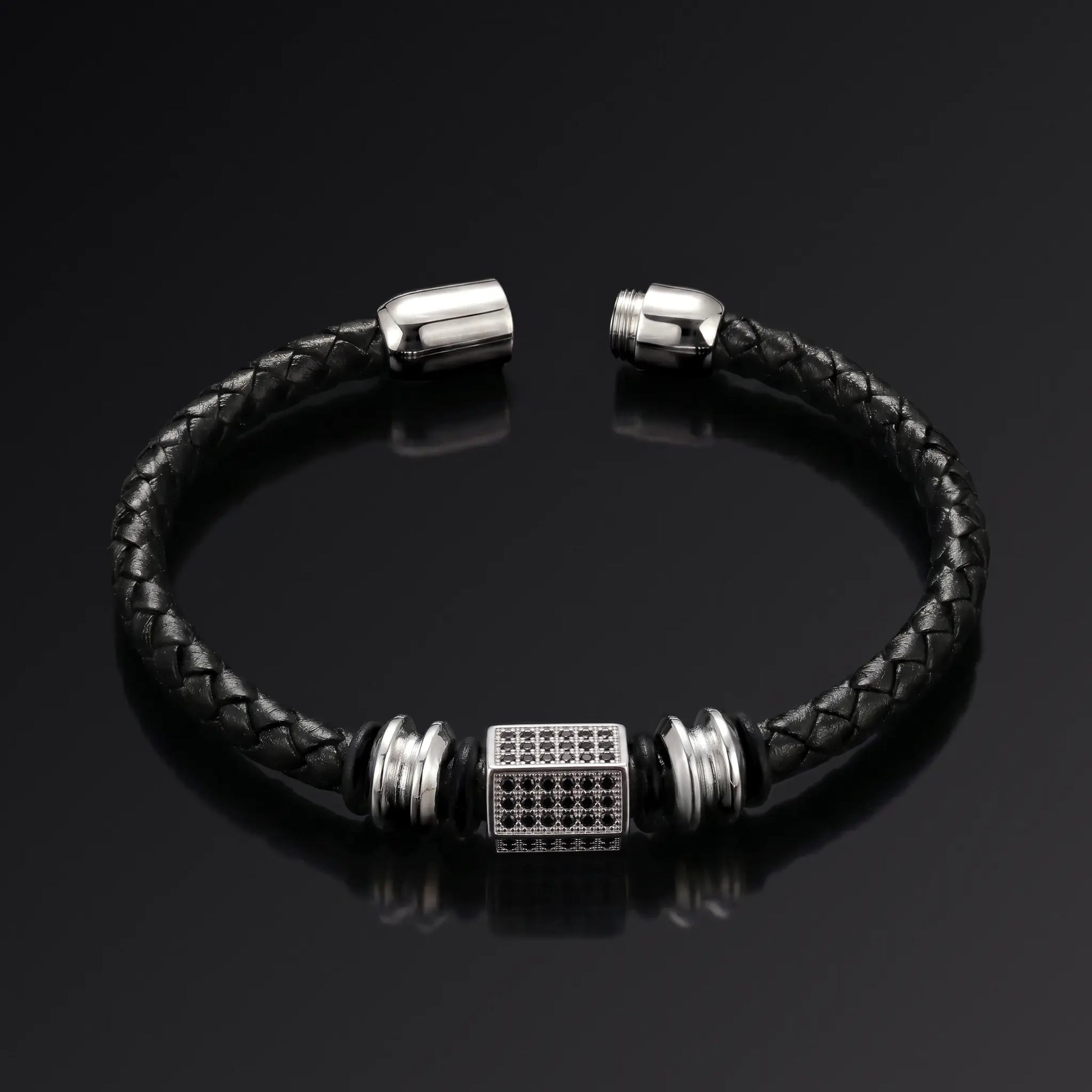 Black braided leather bracelet with silver metal clasp on a black background