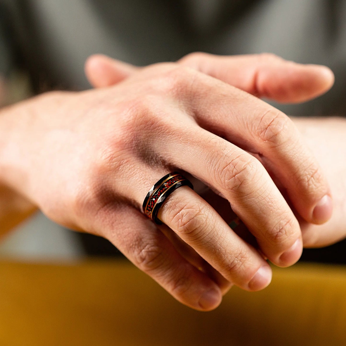 Black hammered tungsten ring with dinosaur bones and meteorite. The ring is on a man's hand