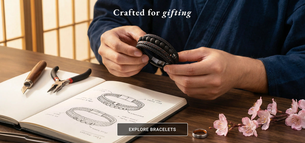 Person holding a bracelet with stationery items and cherry blossoms on a wooden table.