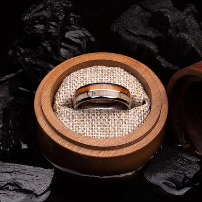 Silver brushed tungsten ring with deer antler and whiskey barrel oak wood. The ring is placed inside a round wooden box