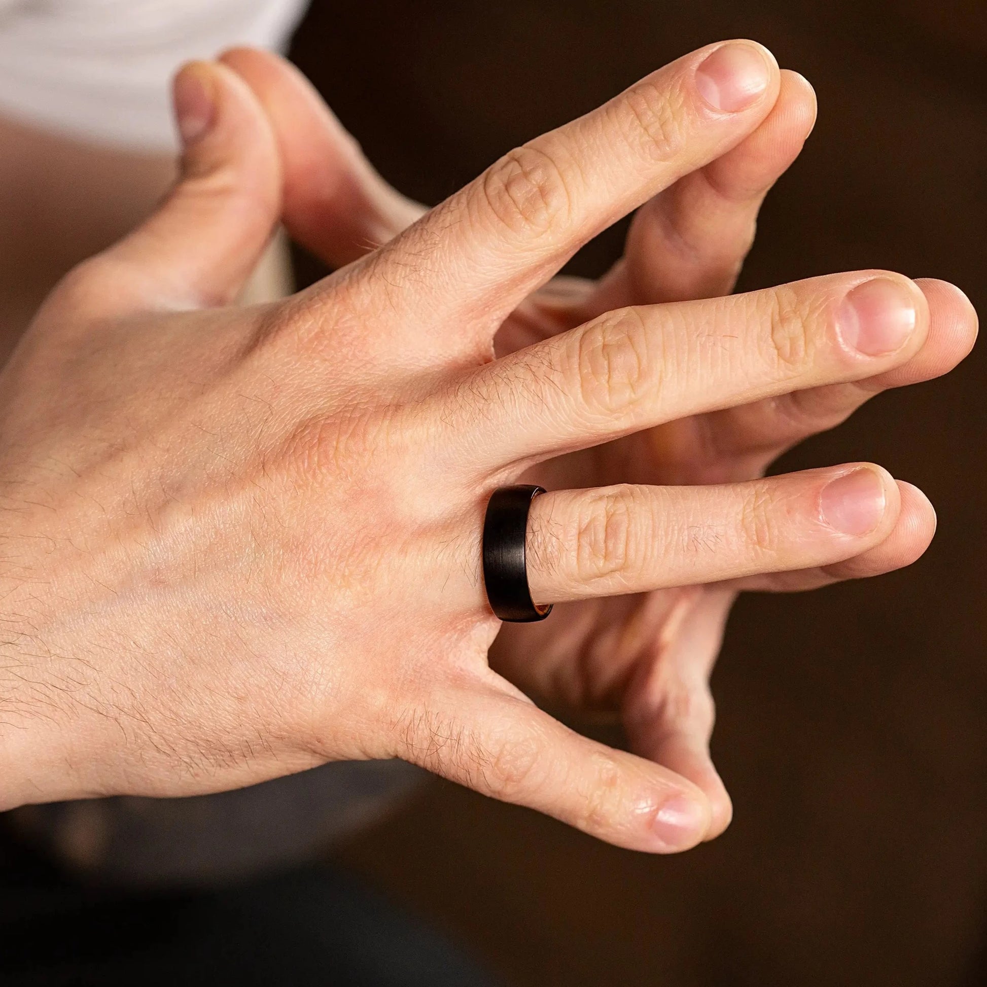 Handcrafted ring made of Oak Wood and Black Tungsten. View on a man hand