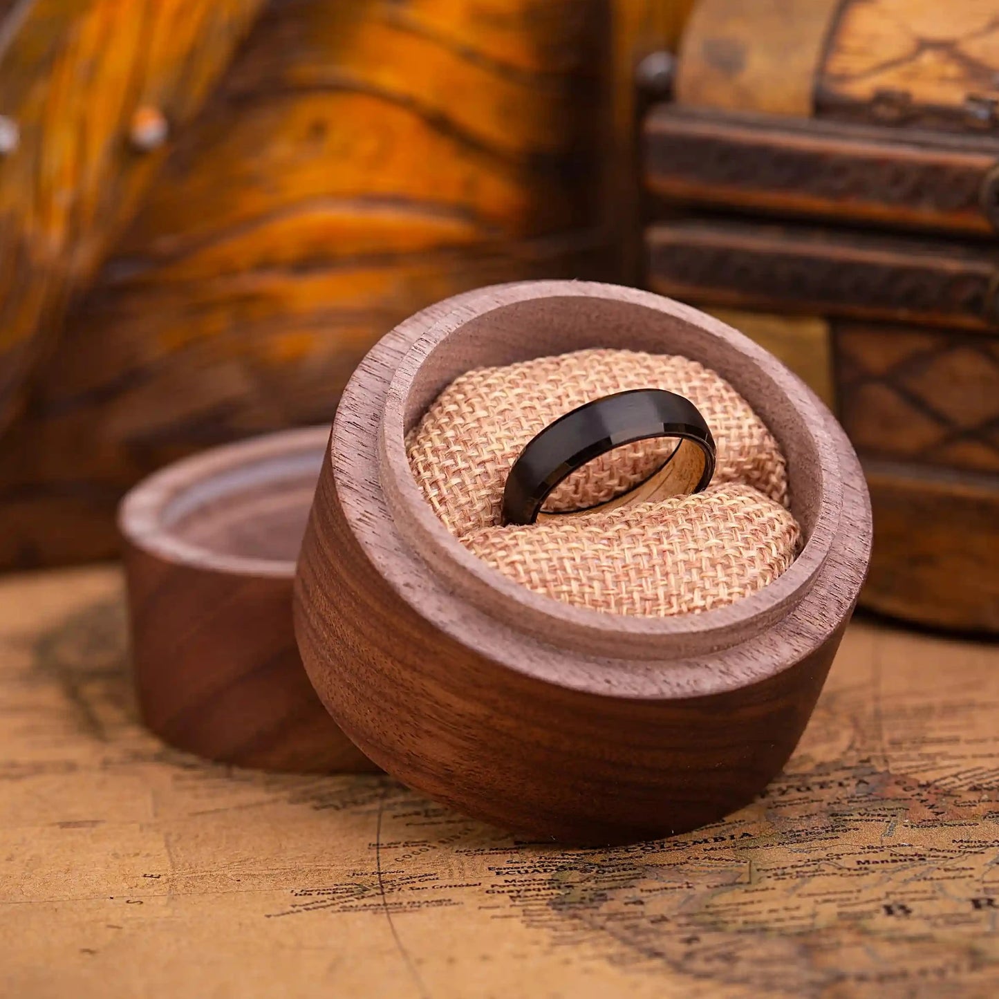 4mm black brushed tungsten ring with whiskey barrel oak wood. The ring is placed inside a round wooden box