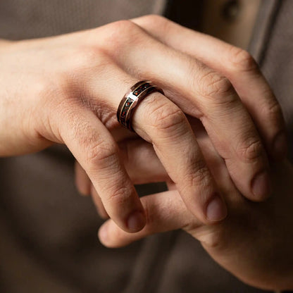 Brown hammered tungsten ring with dinosaur bones and meteorite. The ring is on a man's hand