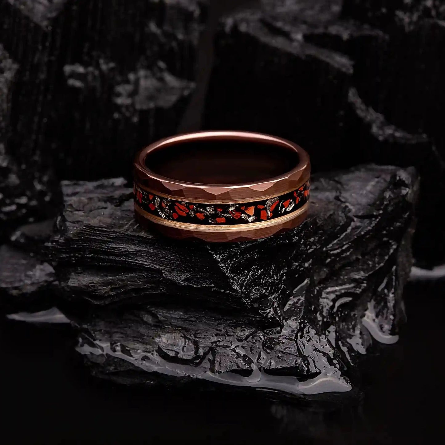 Brown hammered tungsten ring with dinosaur bones and meteorite. The ring is laying on a black coal