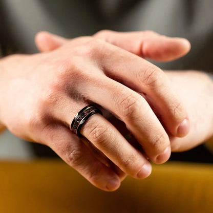 Black hammered tungsten ring with dinosaur bones and meteorite. The ring is on a man's hand