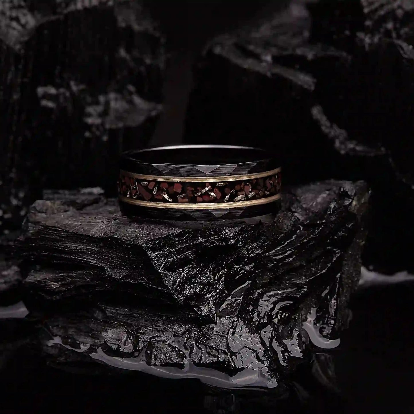 Black hammered tungsten ring with dinosaur bones and meteorite. The ring is laying on a black coal