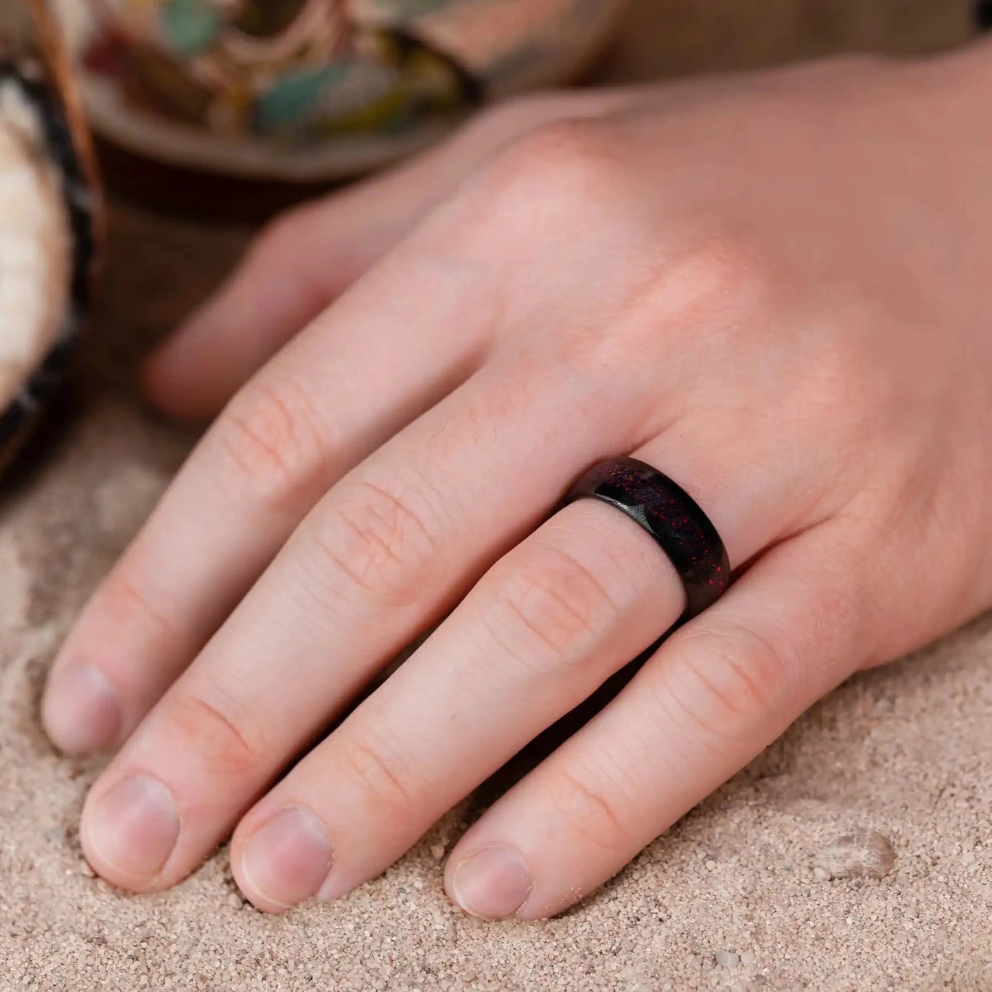 8mm black brushed tungsten ring with red opal. The ring is on a man's hand