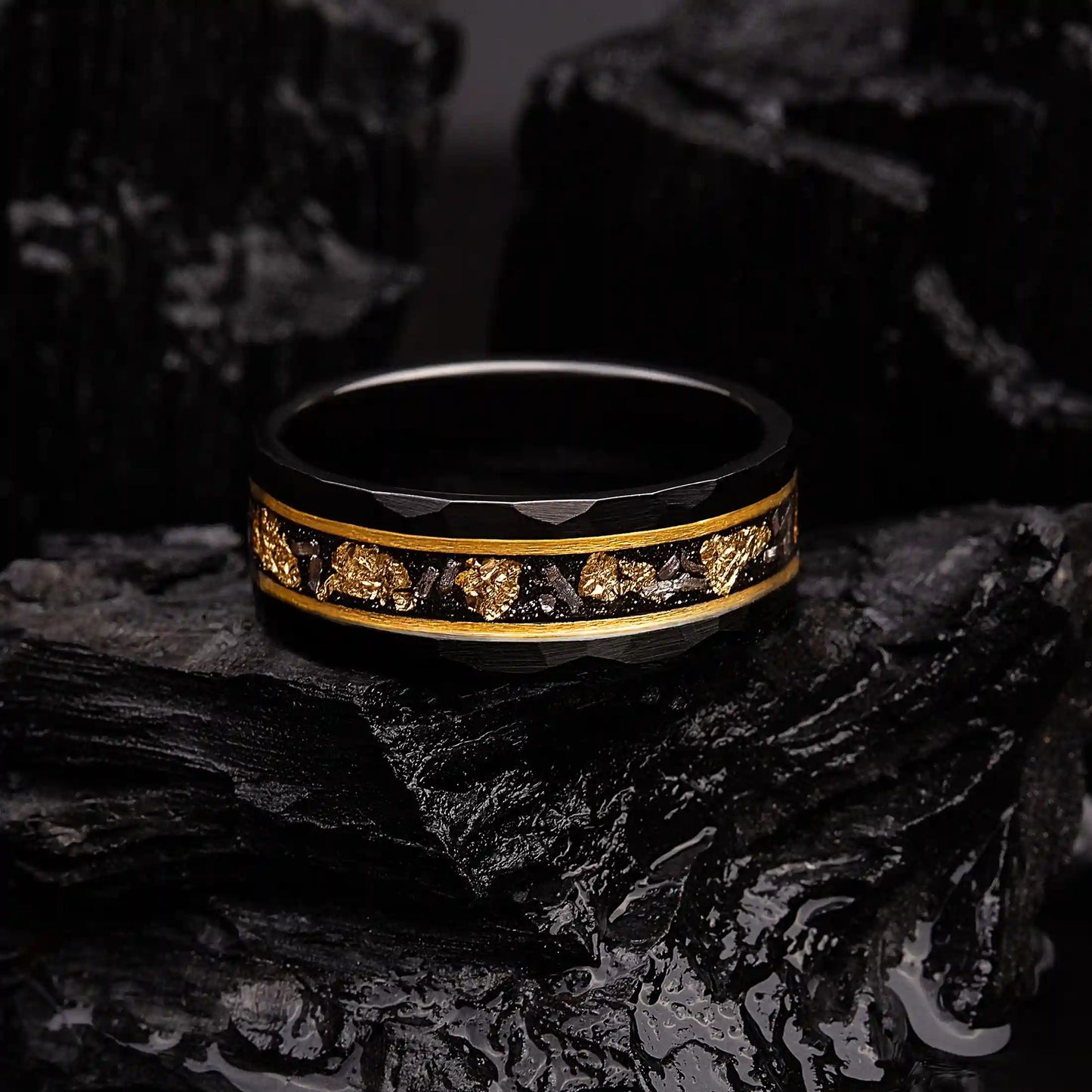 Black hammered tungsten ring with gold and meteorite. The ring is laying on a black coal