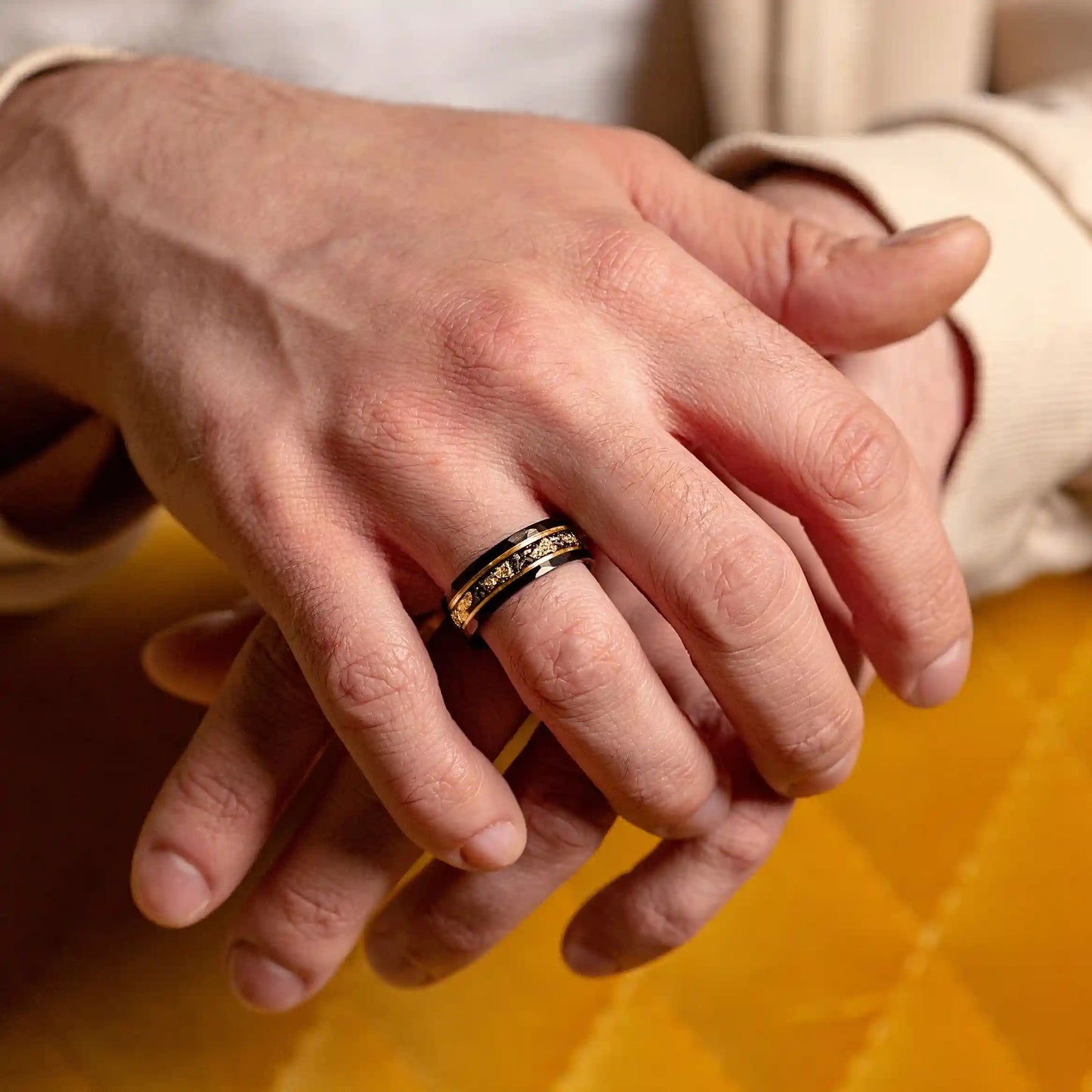 Black hammered tungsten ring with gold and meteorite. The ring is on a man's hand