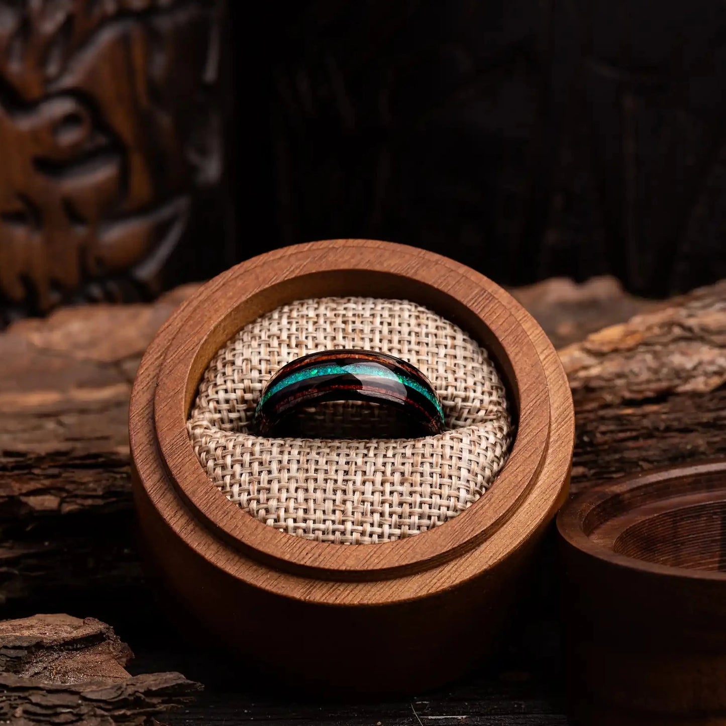 Black polished tungsten ring with green opal and whiskey barrel oak wood. The ring is placed inside a round wooden box