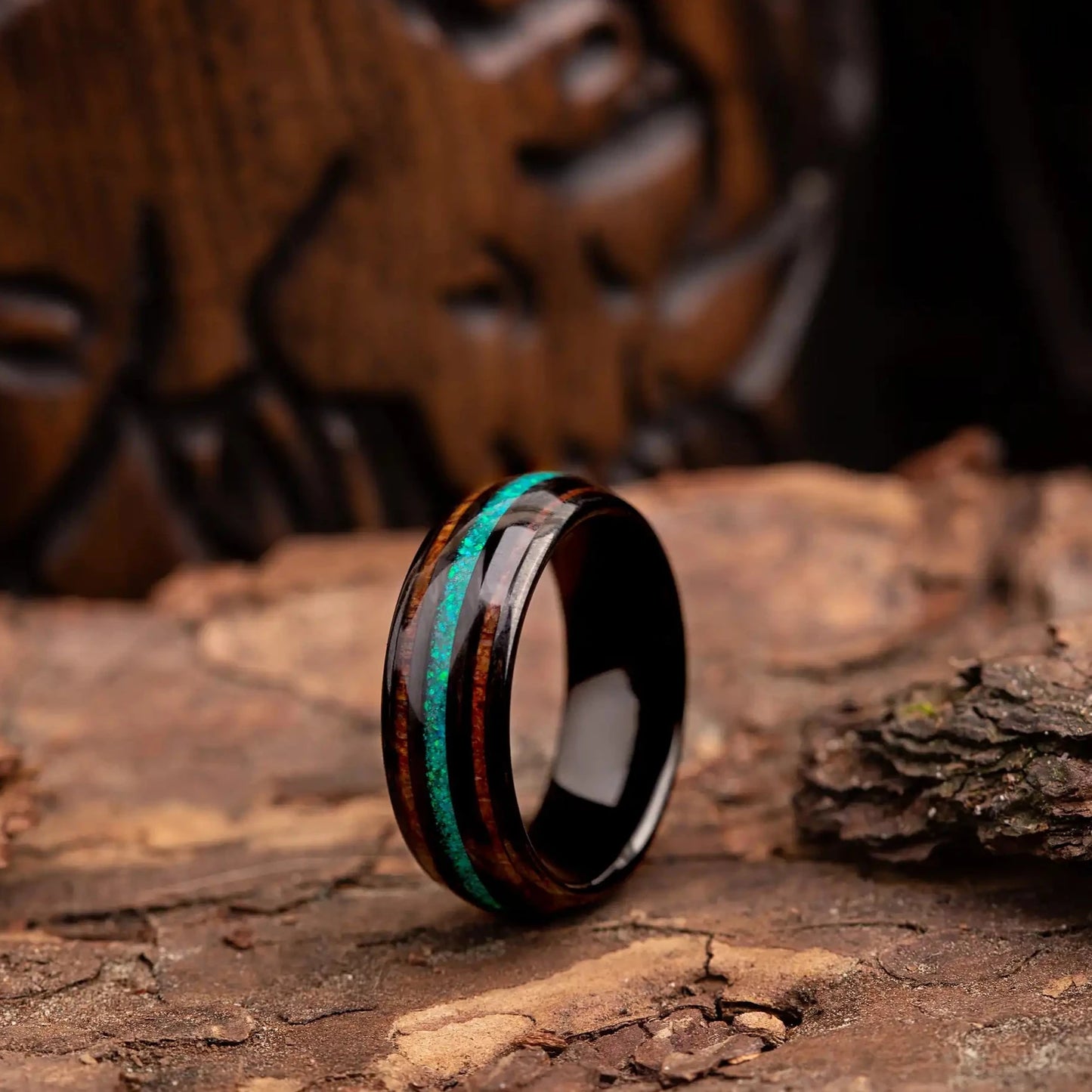 Black polished tungsten ring with green opal and whiskey barrel oak wood. The ring is placed on a wood