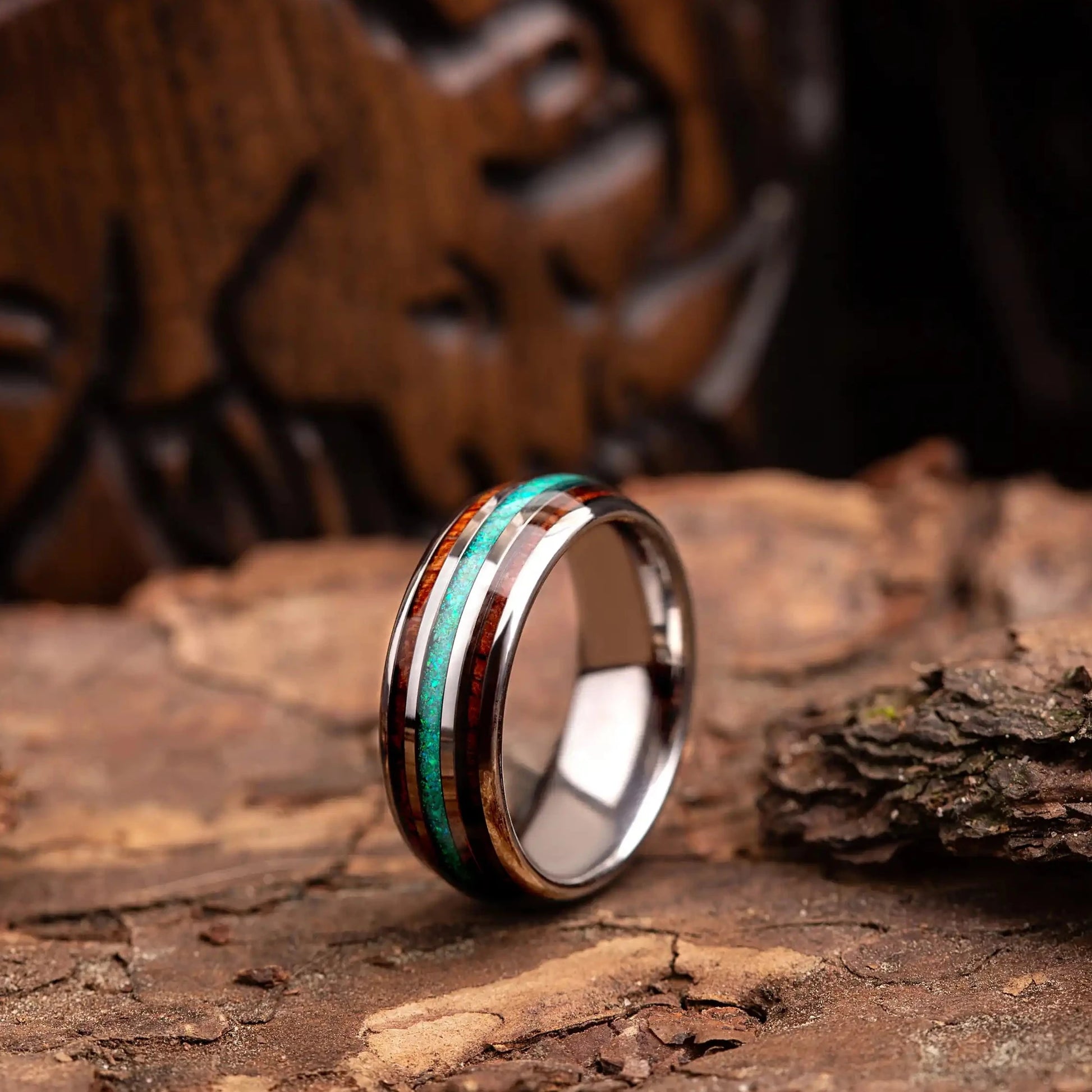 Silver tungsten ring with green opal and whiskey barrel. The ring is placed on a wood