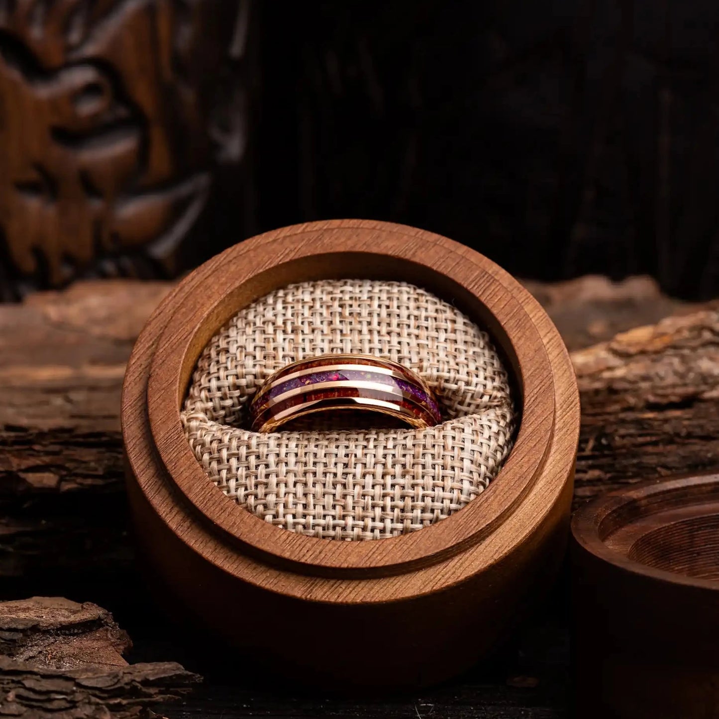 Gold tungsten ring with hawaii wood and red opal. The ring is placed inside a round wooden box