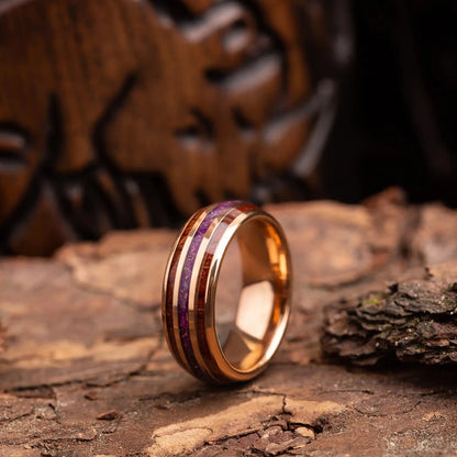 Gold tungsten ring with hawaii wood and red opal. The ring is placed on a wood