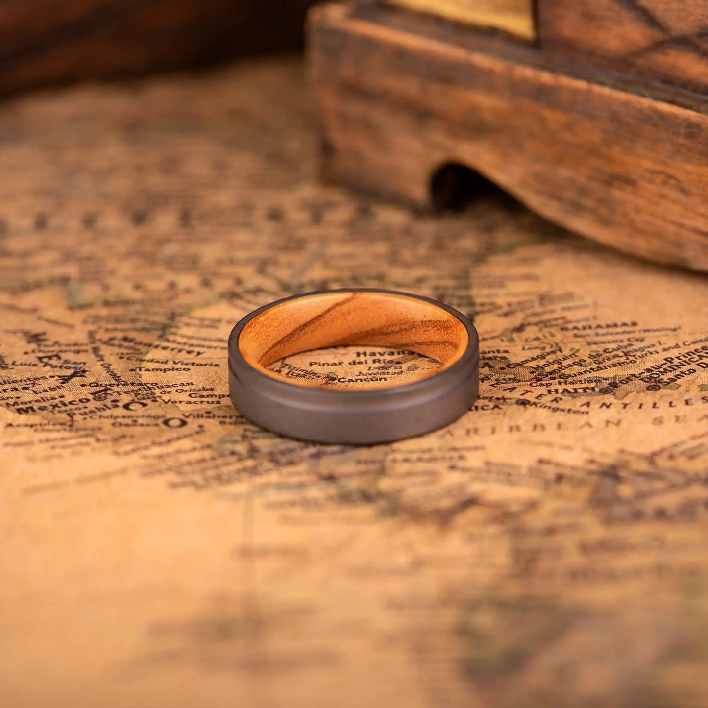 Handcrafted ring made of Oak Wood and Titanium. The ring has a width 4 mm. The ring is laying on a map