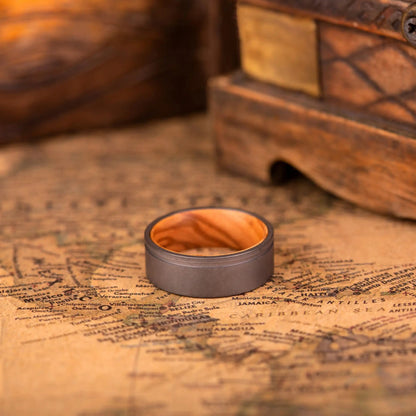 Handcrafted ring made of Oak Wood and Titanium. The ring has a width 8 mm. The ring is laying on a map