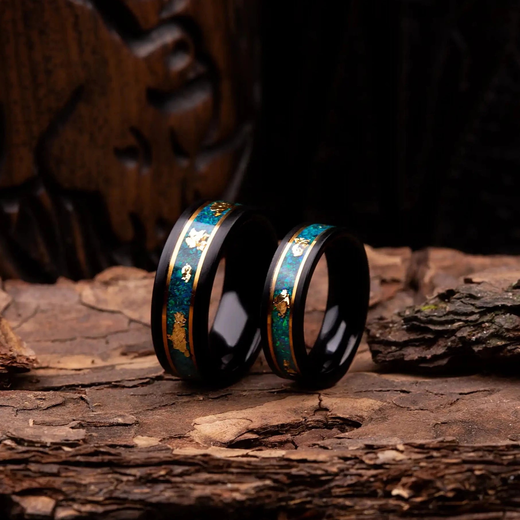 Black polished tungsten ring set for couples with malachite and gold. Rings are placed on a wood