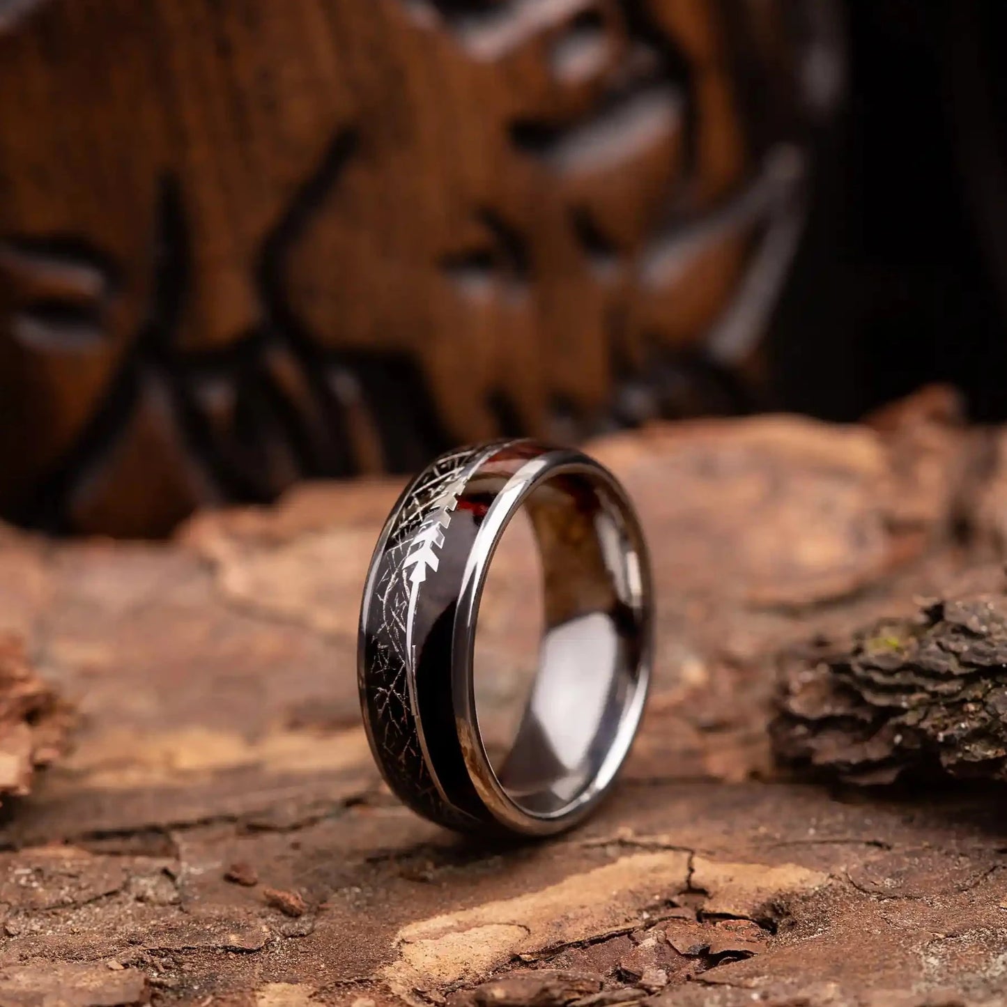 Silver tungsten ring with meteorite, rosewood and arrow sign. The ring is placed on a wood