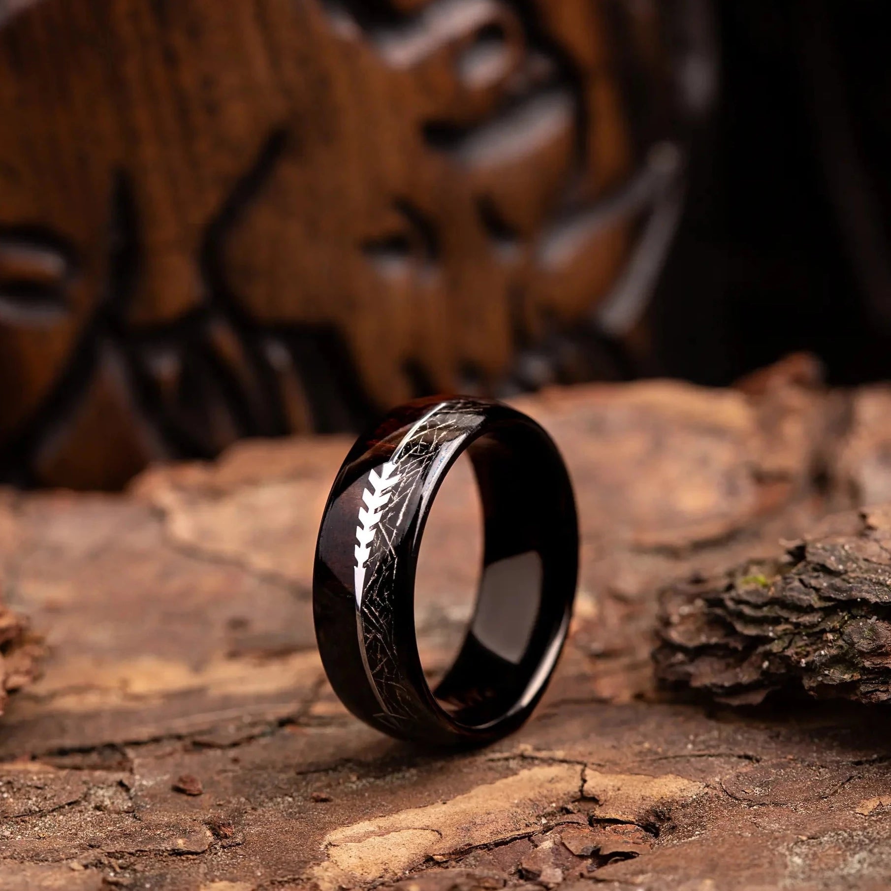 Black tungsten ring with meteorite, rosewood and arrow sign. The ring is placed on a wood