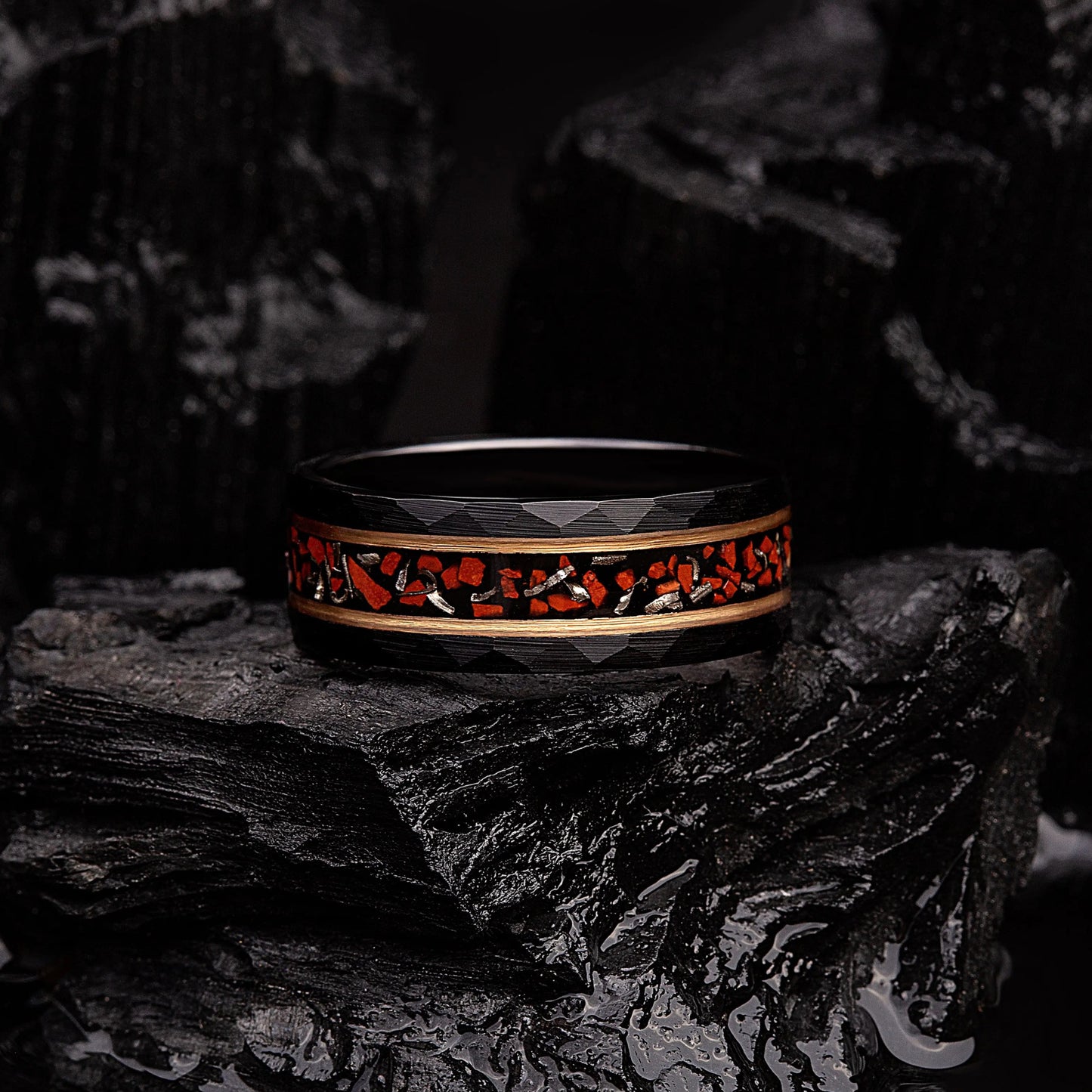 Black hammered tungsten ring with dinosaur bones and meteorite. The ring is laying on a black coal