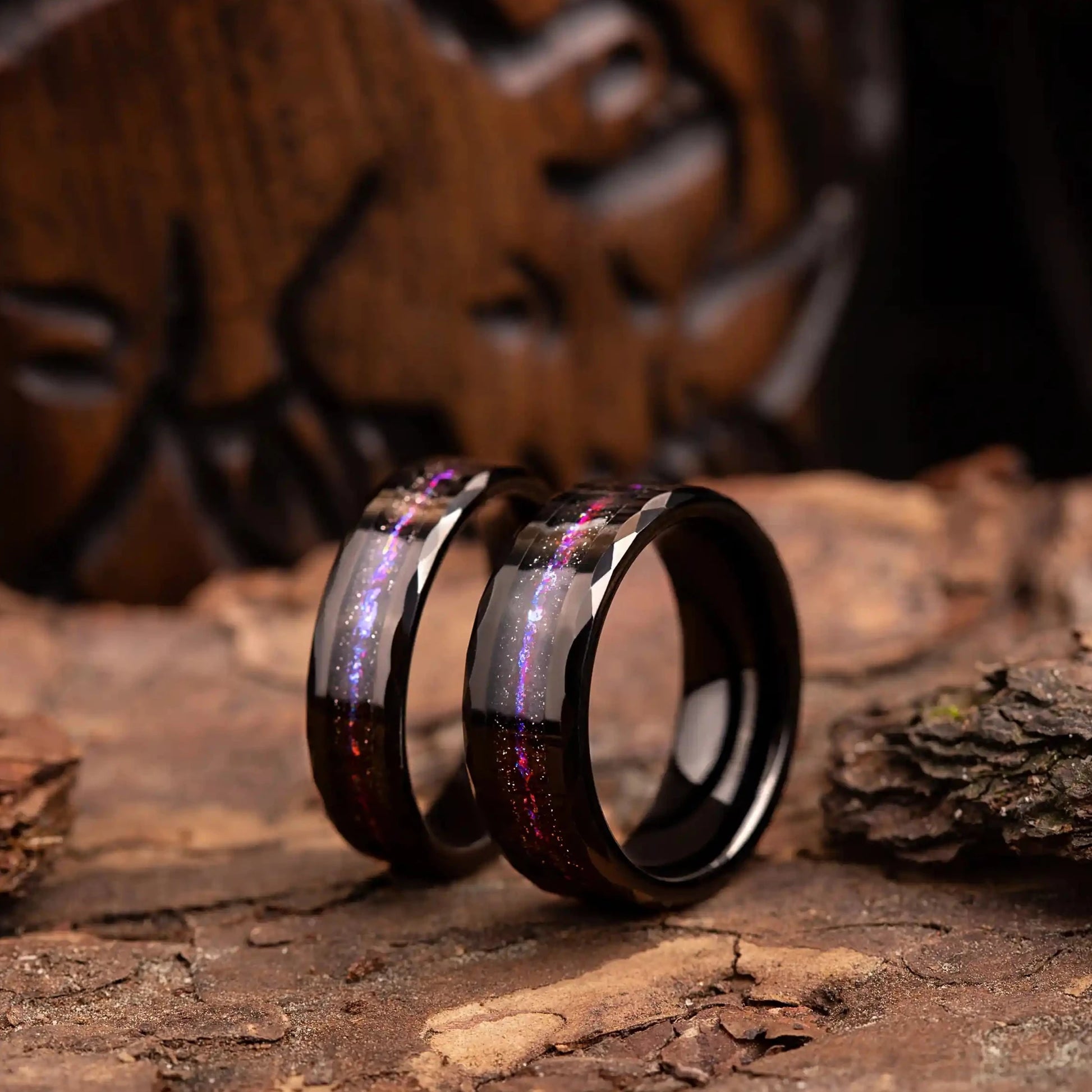 Hammered tungsten ring set for couples with opal and meteorite. Rings are placed on a wood