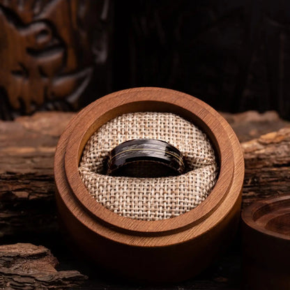 Grey oak wood ring with guitar string. The ring is placed inside a round wooden box