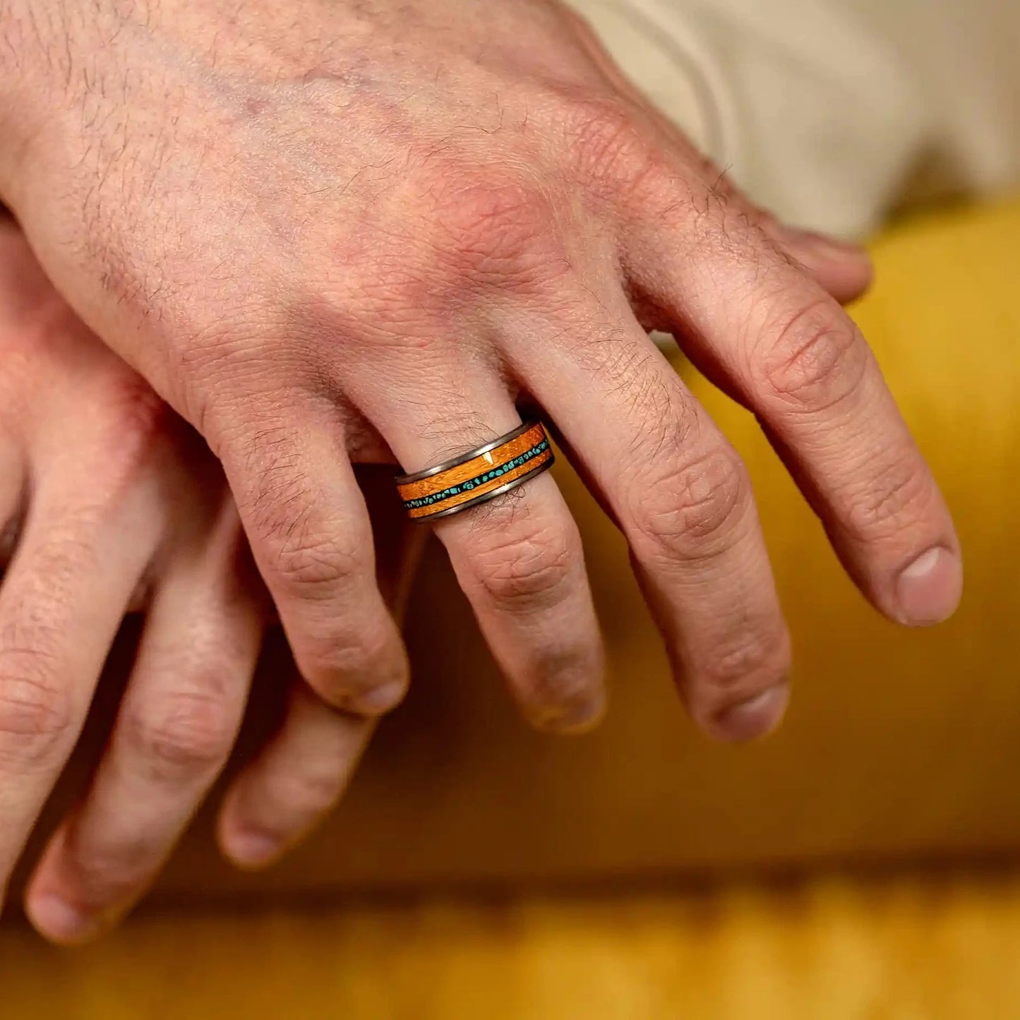 Silver brushed tungsten ring with turquoise and oak wood. The ring is on a man's hand