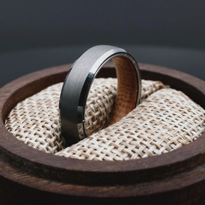 4mm silver brushed tungsten ring with whiskey barrel oak wood inlay. The ring is placed inside a round wooden box