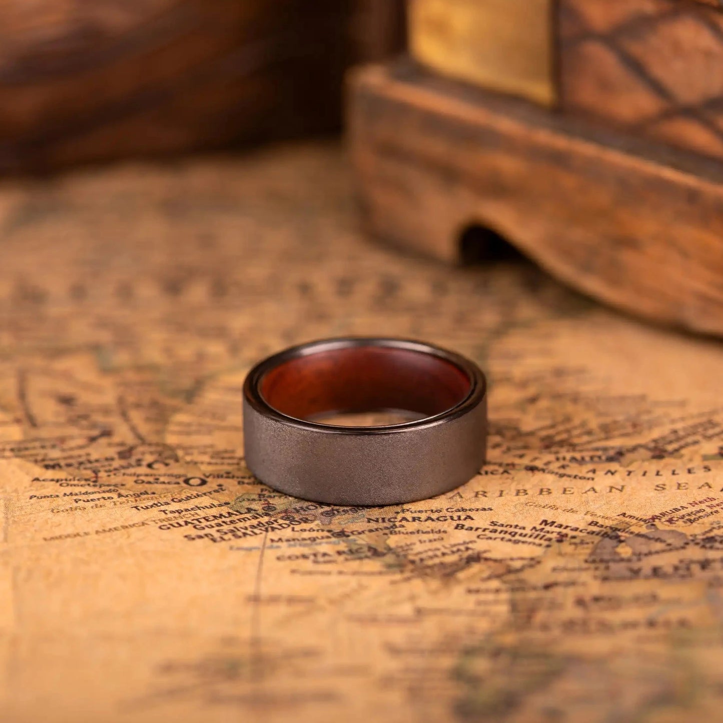 Grey tungsten ring with rosewood inlay. The ring is laying on a map