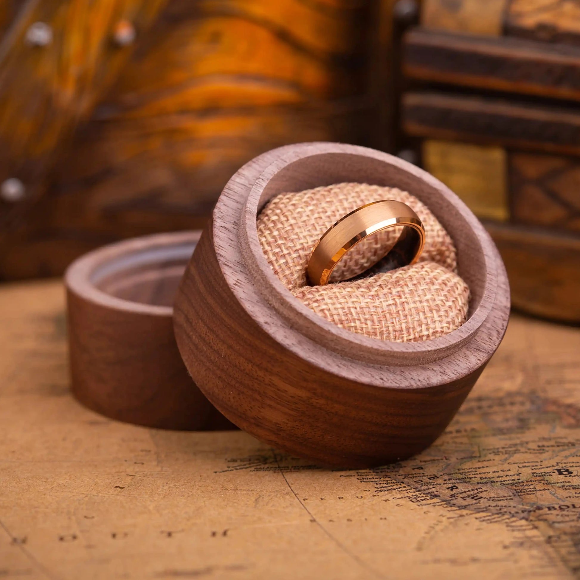 4mm rose titanium ring with whiskey barrel oak wood inlay. The ring is placed inside a round wooden box