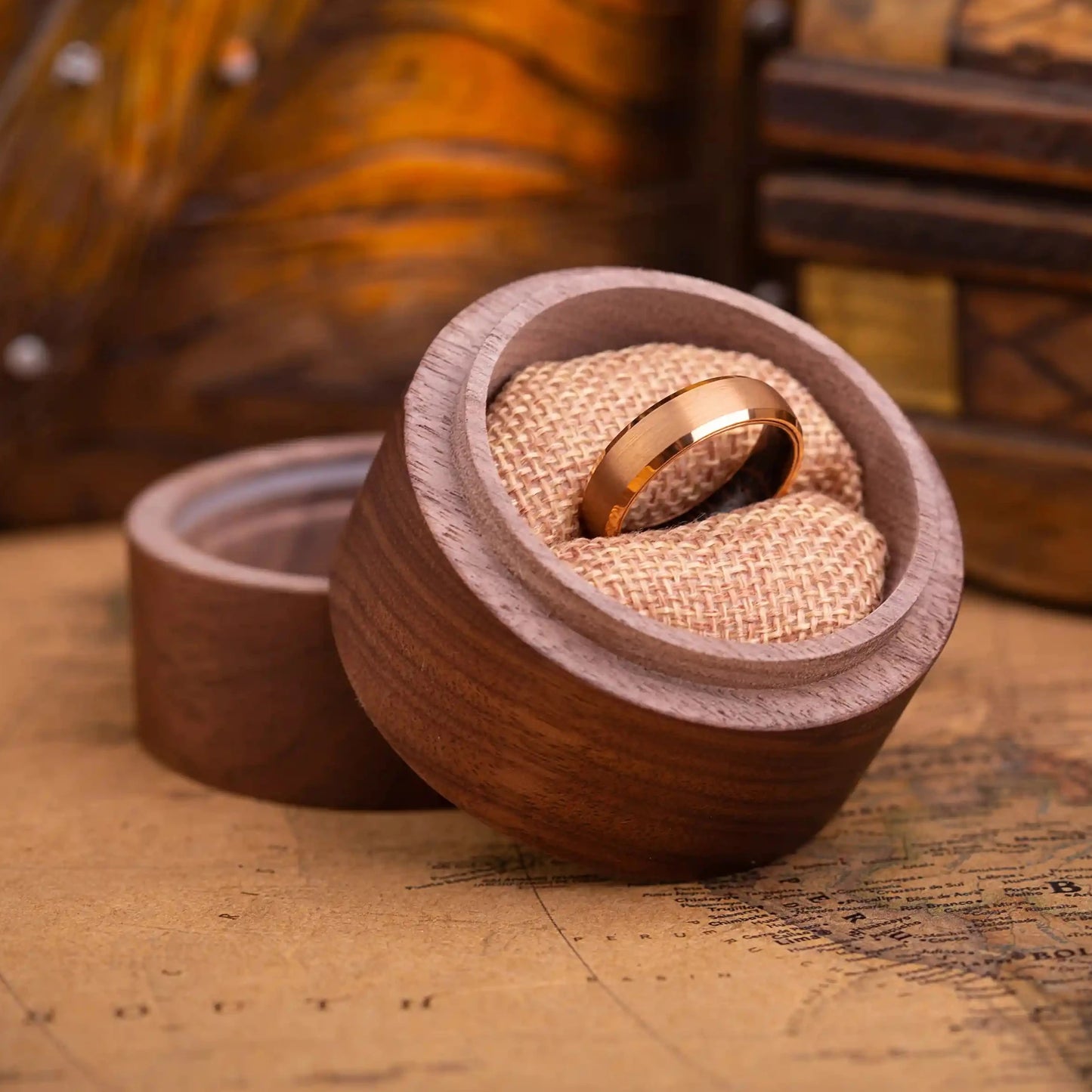 4 mm rose titanium ring with whiskey barrel oak wood inner layer. The ring is placed inside a round wooden box