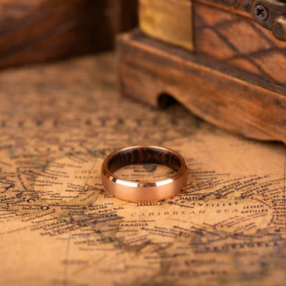 4 mm rose titanium ring with whiskey barrel oak wood inner layer. The ring is laying on a map