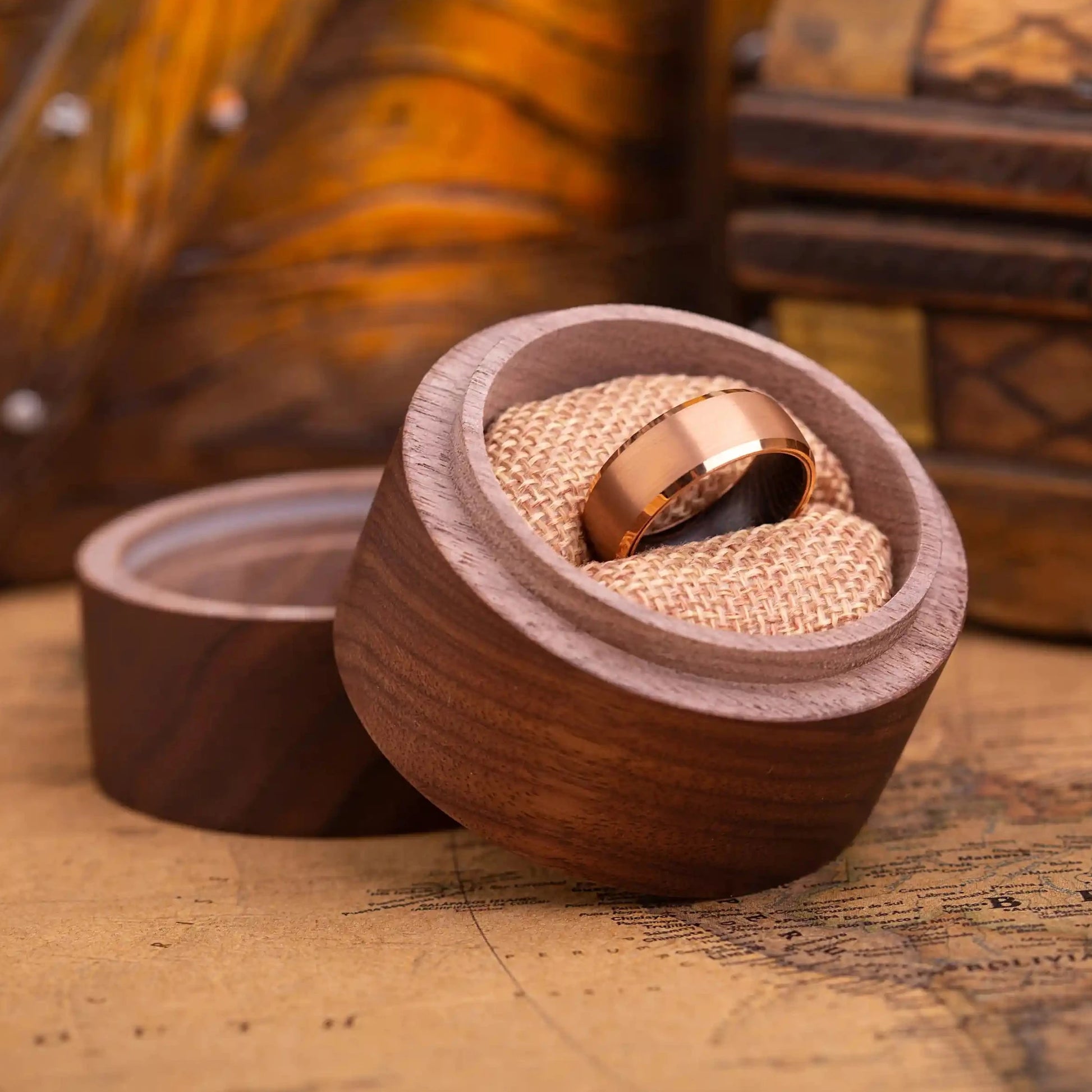 8mm rose titanium ring with whiskey barrel oak wood inlay. The ring is placed inside a round wooden box