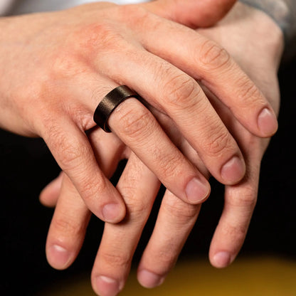 Handcrafted ring made of Sakura wood and Tungsten on a man hand, which holds whiskey glass