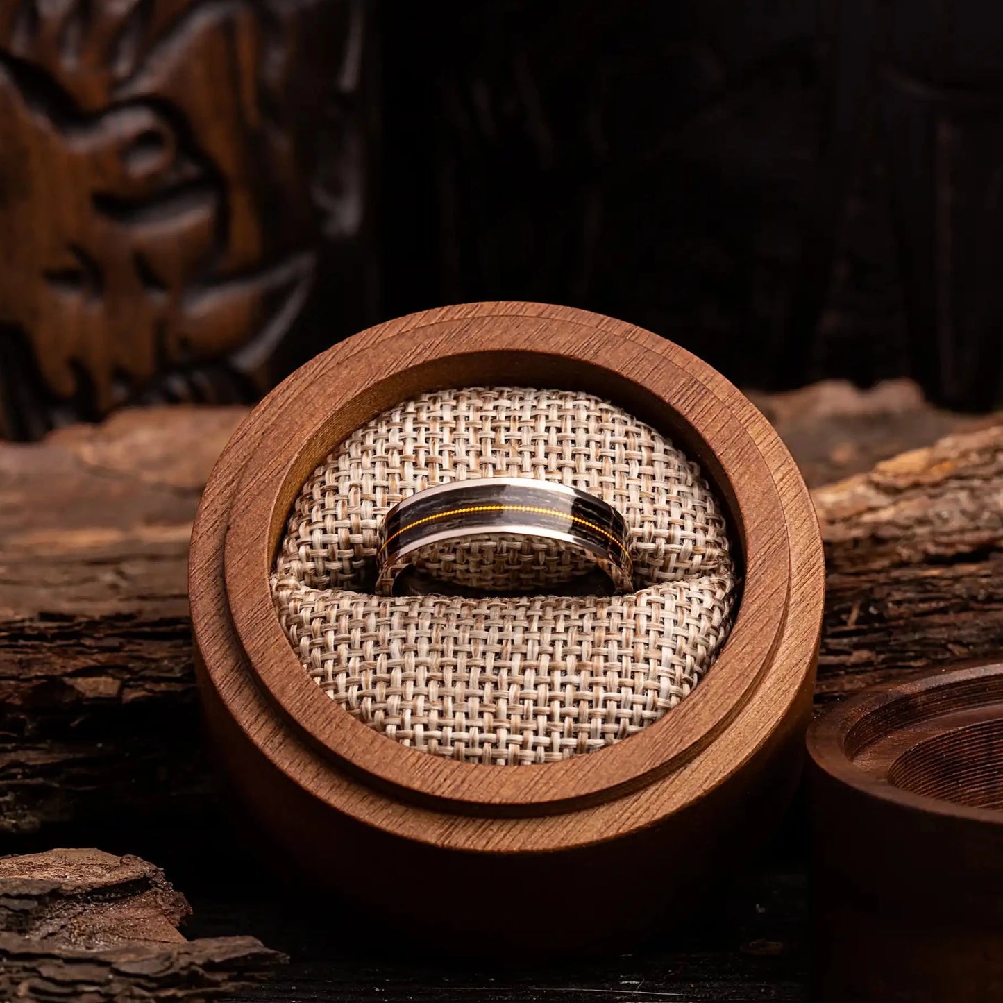 Titanium ring with guitar string and oak wood. The ring is placed inside a round wooden box