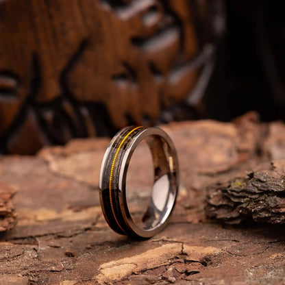 Titanium ring with guitar string and oak wood. The ring is placed on a wood