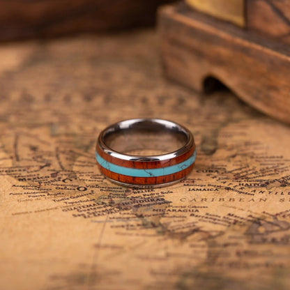 SIlver ring with turquoise and whiskey barrel oak wood in the central inlay. The ring is laying on a map